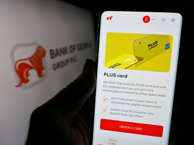 Stuttgart, Almanya - 12-02-2023: Gürcistan Gürcistan Grup plc finans hizmetleri şirketi Bank of Georgia Group plc 'nin web sayfası ile cep telefonu tutan kişi logonun önünde. Telefon ekranının merkezine odaklan.