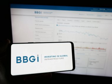 Stuttgart, Almanya - 12-02-2023: Yatırım şirketi BBGI Global Infrastructure SA 'nın logosuna sahip cep telefonu sahibi kişi iş sayfasının önünde. Telefon ekranına odaklan.