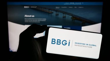 Stuttgart, Almanya - 12-02-2023: Yatırım şirketi BBGI Global Altyapı S.A. 'nın logosuna sahip akıllı telefon sahibi kişi web sitesi önünde. Telefon ekranına odaklan.