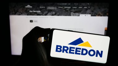 Stuttgart, Almanya - 12-05-2023: İngiliz inşaat malzemeleri şirketi Breedon Group plc 'in logosuna sahip akıllı telefon sahibi kişi web sitesinin önünde. Telefon ekranına odaklan.