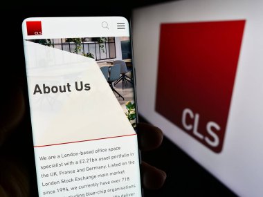 Stuttgart, Almanya - 12-06-2023: İngiliz gayrimenkul yatırım şirketi CLS Holding plc 'nin logolu web sayfası ile cep telefonu tutan kişi. Telefon ekranının merkezine odaklan.