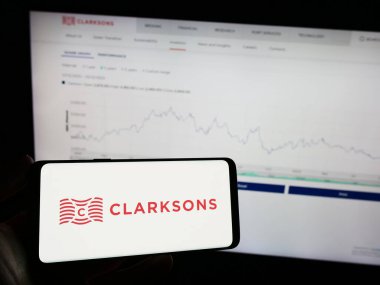 Stuttgart, Almanya - 12-06-2023: İngiliz lojistik şirketi Clarkson plc 'ın (Clarksonlar) logosuna sahip cep telefonu sahibi kişi. Telefon ekranına odaklan.
