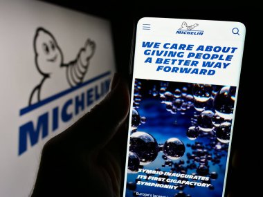 Stuttgart, Almanya - 12-07-2023: Compagnie Generale des Etablissements Michelin SCA 'nın logosu önünde web sayfası bulunan kişi. Telefon ekranının merkezine odaklan.