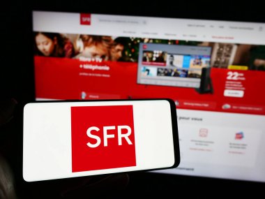 Stuttgart, Almanya - 12-07-2023: İnternet sayfası önünde Fransız Societe Francaise du Radiotelephone (SFR) şirketinin logosuyla cep telefonu tutan kişi. Telefon ekranına odaklan.