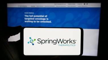 Stuttgart, Almanya - 12-07-2023: Web sayfası önünde ABD 'li biyoteknoloji şirketi SpringWorks Therapeutics Inc.' in logosuyla cep telefonu bulunduran kişi. Telefon ekranına odaklan.