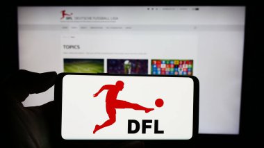 Stuttgart, Almanya - 12-07-2023: Alman futbol şirketi DFL Deutsche Fussball Liga GmbH 'nin logosunun bulunduğu cep telefonu sahibi kişi web sayfası önünde. Telefon ekranına odaklan.