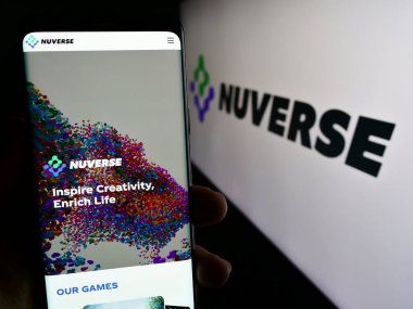 Stuttgart, Almanya - 12-07-2023: Video oyunu şirketi Nuverse 'in (Hong Kong) internet sitesi ile cep telefonu tutan kişi logo önünde sınırlı. Telefon ekranının merkezine odaklan.