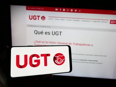 Stuttgart, Almanya - 12-07-2023: İnternet sitesi önünde İspanyol General de Trabajadores 'in (UGT) logosuna sahip kişi. Telefon ekranına odaklan.