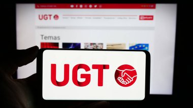 Stuttgart, Almanya - 12-07-2023: İnternet sayfası önünde İspanyol General de Trabajadores 'in (UGT) logosuyla cep telefonu tutan kişi. Telefon ekranına odaklan.