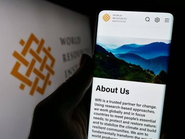 Stuttgart, Almanya - 12-09-2023: Dünya Kaynakları Enstitüsü (WRI) İnternet sitesinin logolu akıllı telefon sahibi kişi. Telefon ekranının merkezine odaklan.