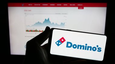 Stuttgart, Almanya - 12-09-2023: Amerikan restoran zinciri şirketi Domino 's Pizza Inc.' in logosunun bulunduğu cep telefonu web sayfasının önünde duruyor. Telefon ekranına odaklan.