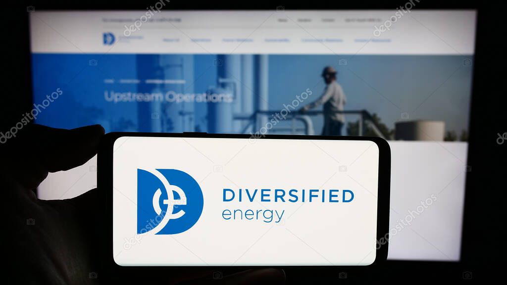 Stuttgart, Germany - 12-08-2023: Person holding smartphone with logo of British business Diversified Energy Company plc in front of website. Focus on phone display.