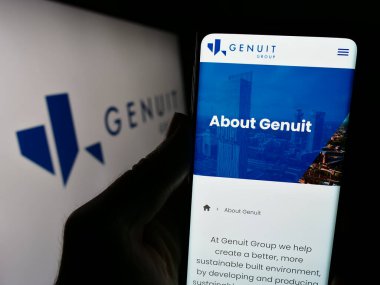 Stuttgart, Almanya - 12-12-2023: İngiliz boru sistemi şirketi Genuit Group plc 'nin web sayfası ile logo önünde cep telefonu tutan kişi. Telefon ekranının merkezine odaklan.