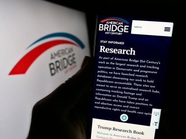 Stuttgart, Almanya - 12-14-2023: Liberal Süper PAC Amerikan Köprüsü 21. yüzyılın logosu önündeki web sayfası ile cep telefonu tutan kişi. Telefon ekranının merkezine odaklan.