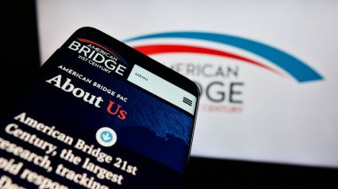 Stuttgart, Almanya - 12-14-2023: Liberal Süper PAC American Bridge 21. yüzyılın logosu önünde bulunan cep telefonu. Telefon ekranının sol üst kısmına odaklan.