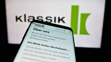 Stuttgart, Almanya - 12-14-2023: Alman yayın şirketi Klassik Radio AG 'nin web sitesi ile birlikte ticaret logosu önünde akıllı telefon. Telefon ekranının sol üst kısmına odaklan.