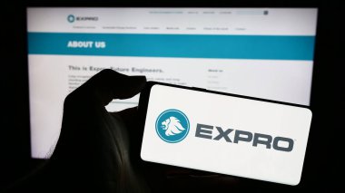 Stuttgart, Almanya - 12-14-2023: İnternet sitesi önünde üzerinde Amerikan petrol ve gaz şirketi Expro Group logosu olan akıllı telefon sahibi kişi. Telefon ekranına odaklan.