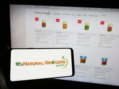 Stuttgart, Almanya - 12-14-2023: Web sayfası önünde Vitamin Kulübesi Şirketi Natural Grocers 'ın logosuna sahip cep telefonu sahibi kişi. Telefon ekranına odaklan.