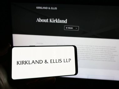 Stuttgart, Almanya - 12-15-2023: İnternet sitesinin önünde ABD 'li hukuk firması Kirkland ve Ellis LLLP' nin logosuna sahip akıllı telefon sahibi kişi. Telefon ekranına odaklan.