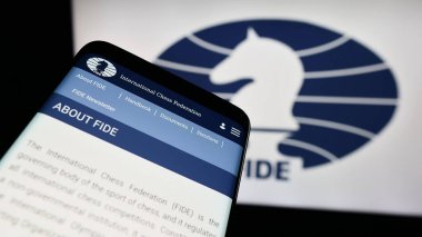 Stuttgart, Germany - 12-15-2023: Mobile phone with website of organisation International Chess Federation (FIDE) in front of logo. Focus on top-left of phone display. clipart