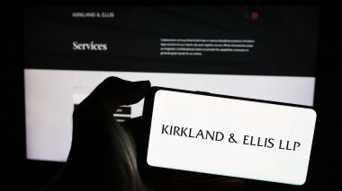 Stuttgart, Almanya - 12-15-2023: Amerikan hukuk firması Kirkland ve Ellis LLLP 'nin logosuna sahip cep telefonu sahibi kişi iş sayfasının önünde. Telefon ekranına odaklan.