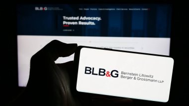Stuttgart, Almanya - 12-15-2023: İnternet sayfasının önünde ABD 'li hukuk firması Bernstein Litowitz Berger ve Grossmann' ın (BLBG) logosuna sahip cep telefonu sahibi kişi. Telefon ekranına odaklan.