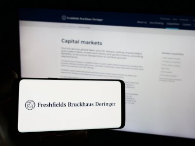 Stuttgart, Almanya - 12-17-2023: İngiliz hukuk firması Freshfields Bruckhaus Deringer LLLP 'nin logosunu elinde tutan kişi. Telefon ekranına odaklan.