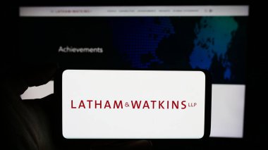 Stuttgart, Almanya - 12-17-2023: İş sayfası önünde ABD 'li hukuk firması Latham ve Watkins LLLP' nin (LW) logosuyla cep telefonu tutan kişi. Telefon ekranına odaklan.