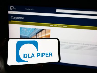 Stuttgart, Almanya - 12-17-2023: Üzerinde hukuk firması DLA Piper 'ın logosu olan cep telefonu sahibi kişi iş sayfasının önünde. Telefon ekranına odaklan.
