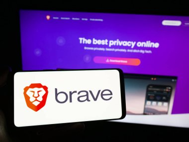 Stuttgart, Almanya - 12-18-2023: Web tarayıcı şirketi Brave Software Inc. 'in logosuna sahip akıllı telefon sahibi kişi web sitesinin önünde. Telefon ekranına odaklan.