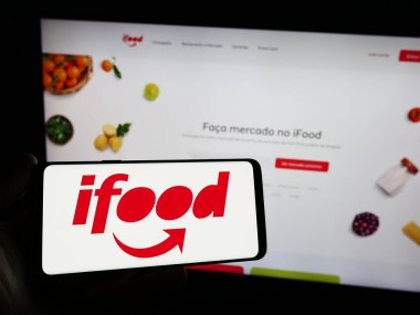 Stuttgart, Almanya - 12-18-2023: Elinde Brezilya gıda siparişi ve iFood dağıtım şirketinin logosunun bulunduğu akıllı telefon bulunduran kişi. Telefon ekranına odaklan.