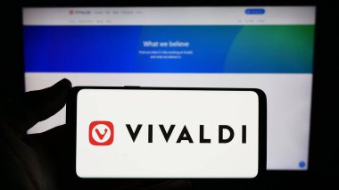 Stuttgart, Germany - 12-18-2023: Person holding smartphone with logo of Norwegian web browser company Vivaldi Technologies AS in front of website. Focus on phone display. clipart