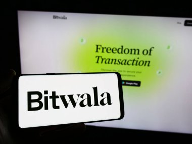Stuttgart, Almanya - 12-18-2023: Alman fintech şirketi Bitwala GmbH 'nin logosuna sahip akıllı telefon sahibi kişi web sitesinin önünde. Telefon ekranına odaklan.