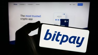 Stuttgart, Almanya - 12-18-2023: İnternet sitesi önünde üzerinde ABD kripto para ödeme şirketi BitPay Inc. 'in logosu bulunan akıllı telefon sahibi kişi. Telefon ekranına odaklan.