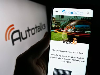 Stuttgart, Germany - 12-18-2023: Person holding smartphone with webpage of Israeli automotive technology company Autotalks Ltd. in front of logo. Focus on center of phone display. clipart