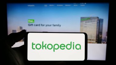Stuttgart, Almanya - 12-20-2023: Endonezyalı e-ticaret şirketi PT Tokopedia 'nın logosunu elinde tutan kişi. Telefon ekranına odaklan.
