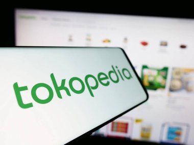 Stuttgart, Germany - 12-20-2023: Smartphone with logo of Indonesian e-commerce company PT Tokopedia in front of business website. Focus on center-left of phone display. clipart