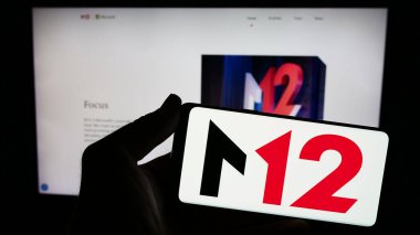 Stuttgart, Almanya - 12-20-2023: Sitenin önünde ABD 'li risk sermayesi şirketi M12' nin (Microsoft) logosuna sahip akıllı telefon sahibi kişi. Telefon ekranına odaklan.