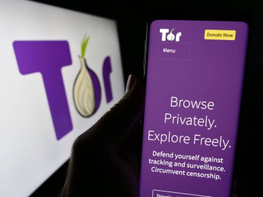Stuttgart, Almanya - 12-20-2023: Logolu Onion Router (TOR) adlı anonim iletişim yazılımının web sitesine sahip kişi. Telefon ekranının merkezine odaklan.
