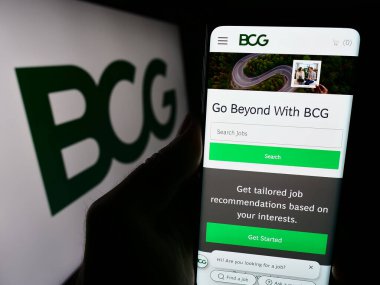 Stuttgart, Almanya - 12-20-2023: ABD 'li Boston Consulting Group Inc. (BCG) şirketinin web sitesi ile logo önünde cep telefonu bulunduran kişi. Telefon ekranının merkezine odaklan.