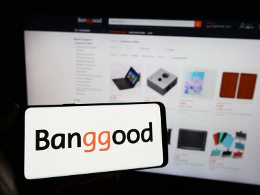 Stuttgart, Almanya - 12-20-2023: Çinli e-ticaret şirketi Banggood 'un logosunun bulunduğu cep telefonu sahibi kişi iş sayfasının önünde. Telefon ekranına odaklan.