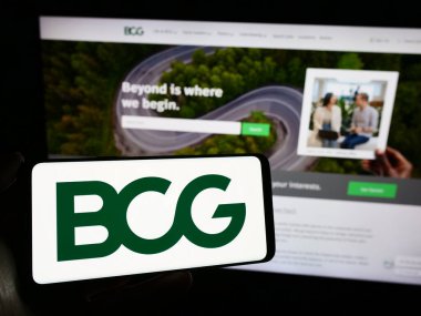Stuttgart, Almanya - 12-20-2023: Amerikan şirketi Boston Danışmanlık Grubu (BCG) logosu olan cep telefonu sahibi kişi web sayfasının önünde. Telefon ekranına odaklan.