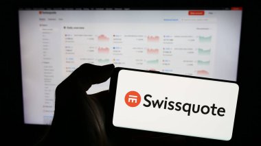 Stuttgart, Germany - 12-22-2023: Person holding smartphone with logo of Swiss financial services company Swissquote in front of website. Focus on phone display. clipart