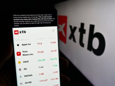 Stuttgart, Almanya - 12-22-2023: Polonyalı yatırım simsarı XTB SA 'nın web sayfası ile birlikte iş logosu önünde cep telefonu tutan kişi. Telefon ekranının merkezine odaklan.