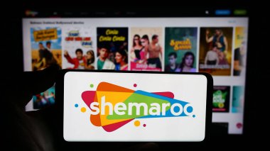 Stuttgart, Almanya - 12-22-2023: Hintli Shemaroo Entertainment Ltd. 'nin logosuna sahip akıllı telefon sahibi kişi web sitesinin önünde. Telefon ekranına odaklan.