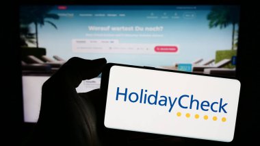 Stuttgart, Almanya - 11-02-2023: Cep telefonunda İsviçreli seyahat portalı şirketi HolidayCheck AG 'nin logosu bulunan kişi web sayfasının önünde. Telefon ekranına odaklan.
