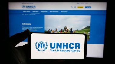Stuttgart, Almanya - 11-02-2023: Web sitesi önünde Birleşmiş Milletler Mülteciler Yüksek Komiserliği (UNHCR) logosu olan akıllı telefon sahibi kişi. Telefon ekranına odaklan.