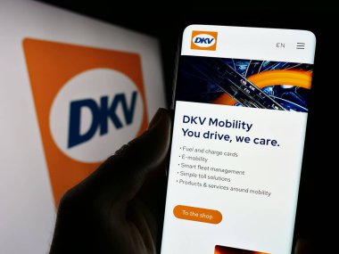 Stuttgart, Almanya - 11-02-2023: İş logosu önünde Alman B2B ödeme şirketi DKV Mobility 'nin web sayfası ile cep telefonu tutan kişi. Telefon ekranının merkezine odaklan.