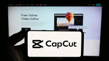 Stuttgart, Almanya - 11-02-2023: Web sitesi önünde video düzenleme uygulaması CapCut logosu olan akıllı telefon sahibi kişi. Telefon ekranına odaklan.