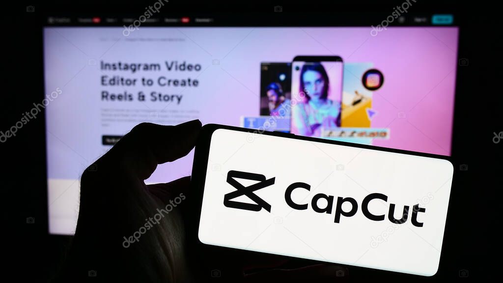 Stuttgart, Germany - 11-02-2023: Person holding mobile phone with logo of video editing app CapCut in front of business web page. Focus on phone display.